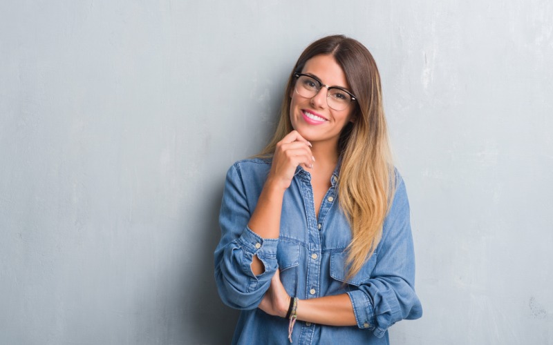 young-adult-woman-grunge grey wall wearing glasses hand chin