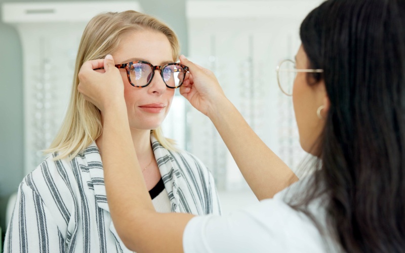 vision-optometrist-help-customer-with-glasses-eye-health-wellness-care-ophthalmology-lens frame woman fitting client choice spectacles eyesight
